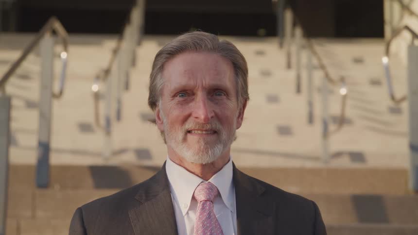A man in a suit standing at the bottom of a set of stairs at an office