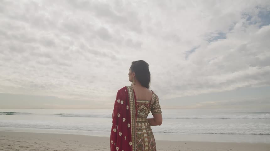 A woman standing on the shore as waves roll in