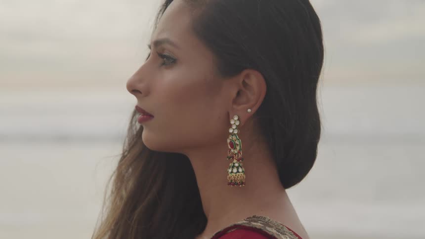 Profile of a young hindu womans face on the beach at sunset next to the ocean