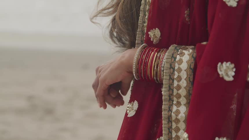 A woman wearing red robes stands in the desert