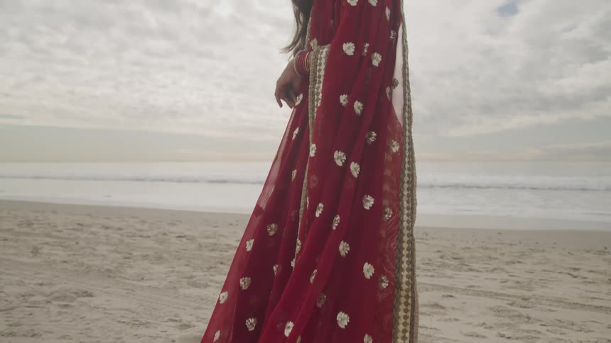 A woman is standing by the coast of a beach