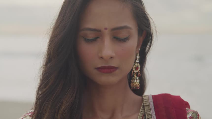 Middle eastern woman stands still with her eyes closed as she wears a fancy earring