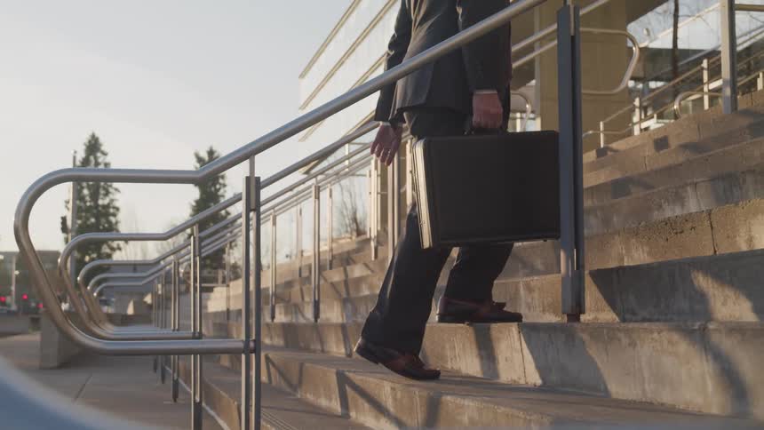 A man is walking up a flight of stairs while holding a suitcase