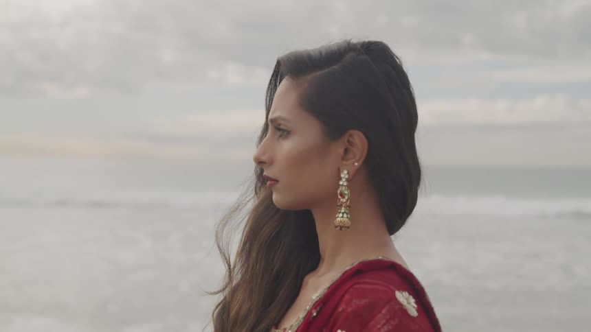 A woman is standing on the beach on a cloudy day