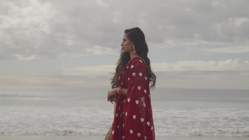 A woman is walking on the coast of a beach