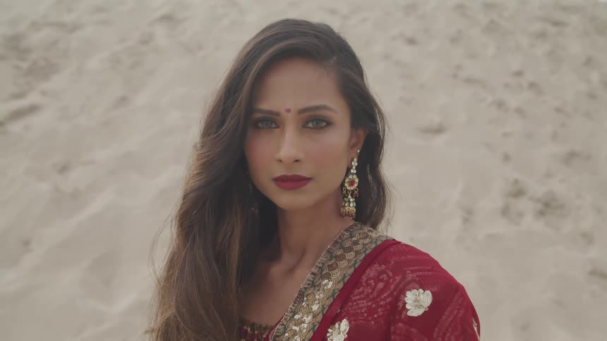 A woman poses in the desert while wearing a sari and bindi