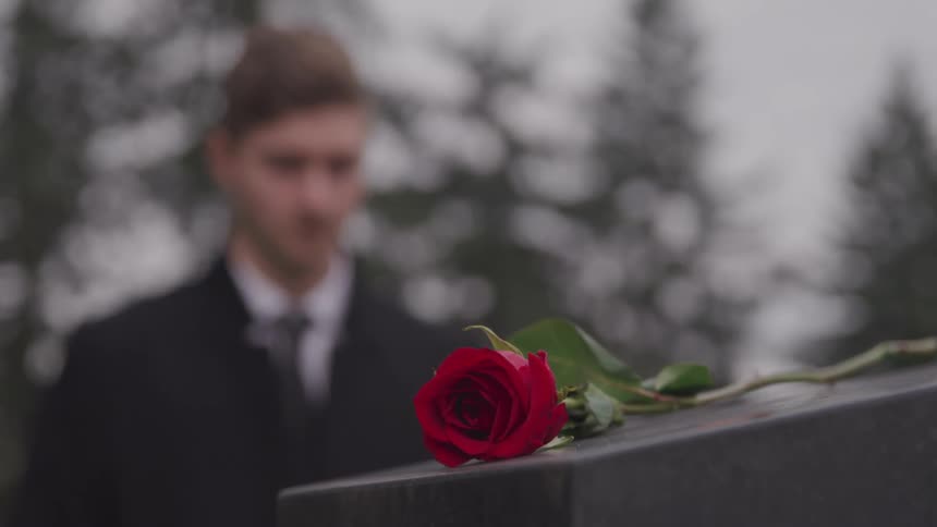 A rose sits on a tombstone in the cemetery