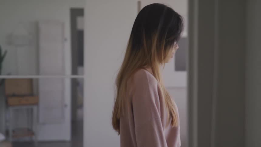 A sad looking teenager walks through her home
