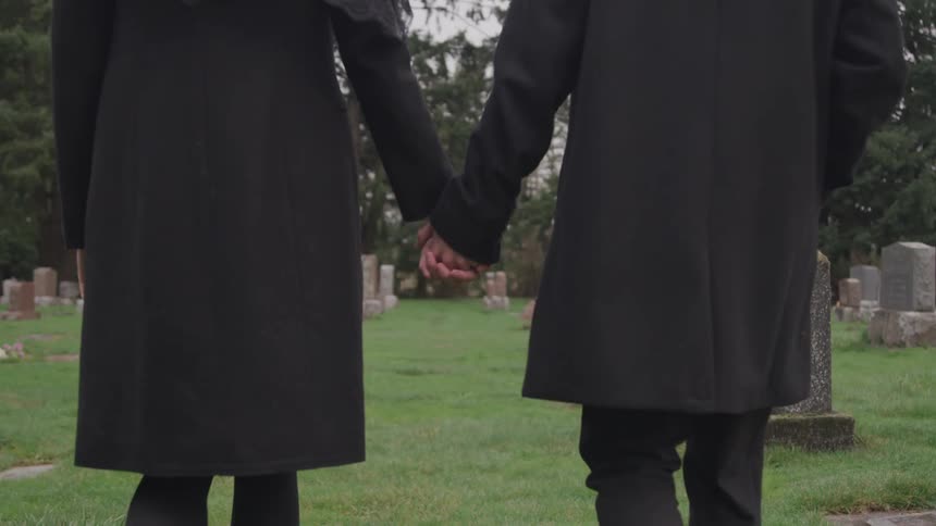 Two people walk through the cemetery together