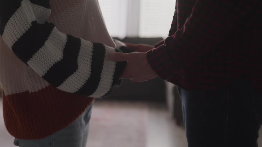 Man and woman stand facing each other then hold each others hands