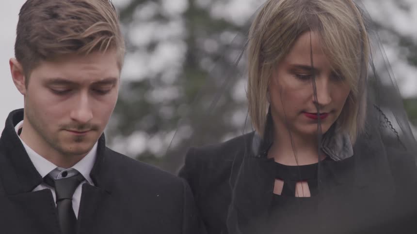 A man and woman grieving at a funeral