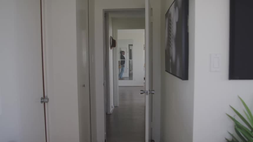 A young man paces back and forth in a room at the end of a hallway of his residence