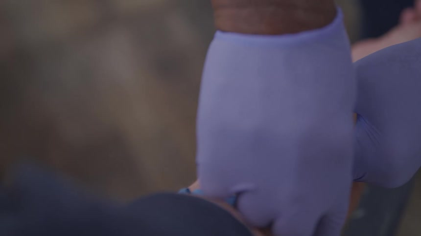 A person with gloves sticking a syringe in another persons arm