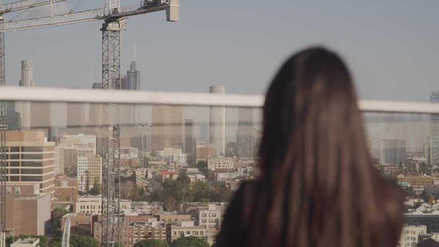 A woman is standing outdoors and looking at a downtown city
