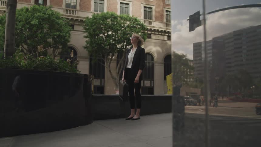 A woman stands around the corner near the building