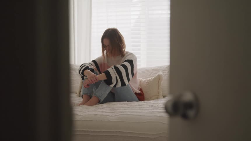 A woman is sitting on a bed in a bedroom