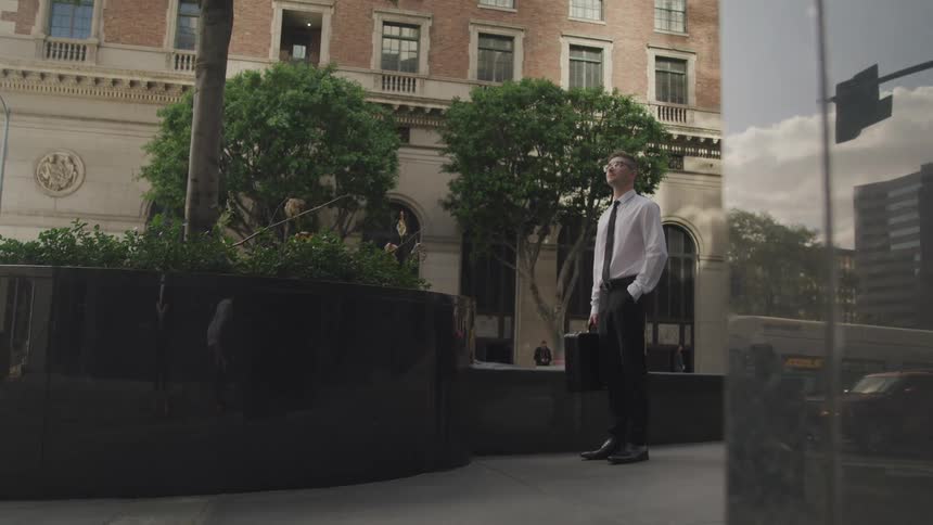A man is standing outdoors in a downtown city