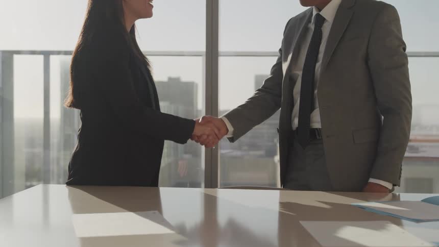 A man and woman shake hands in an office