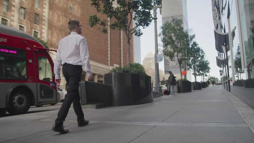 Businessman carrying a black briefcase walks down the street in the city