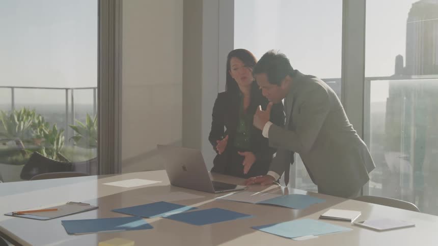 Asian businessman and businesswoman stand and look at laptop in the office