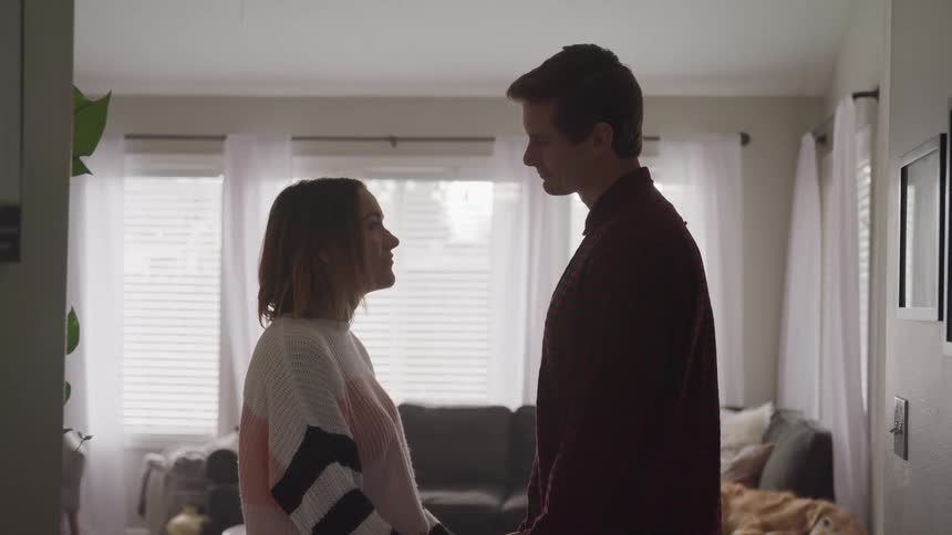 Couple hold hands and looks into each others eyes in the living room at home