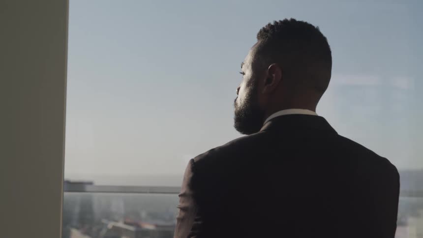 A man looks out of his office window at the city skyline