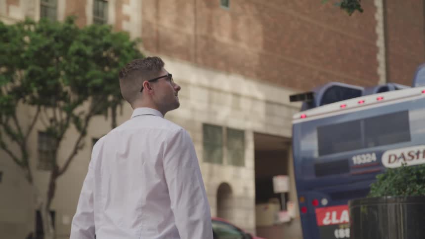 Man with a white shirt and glasses walks down the street