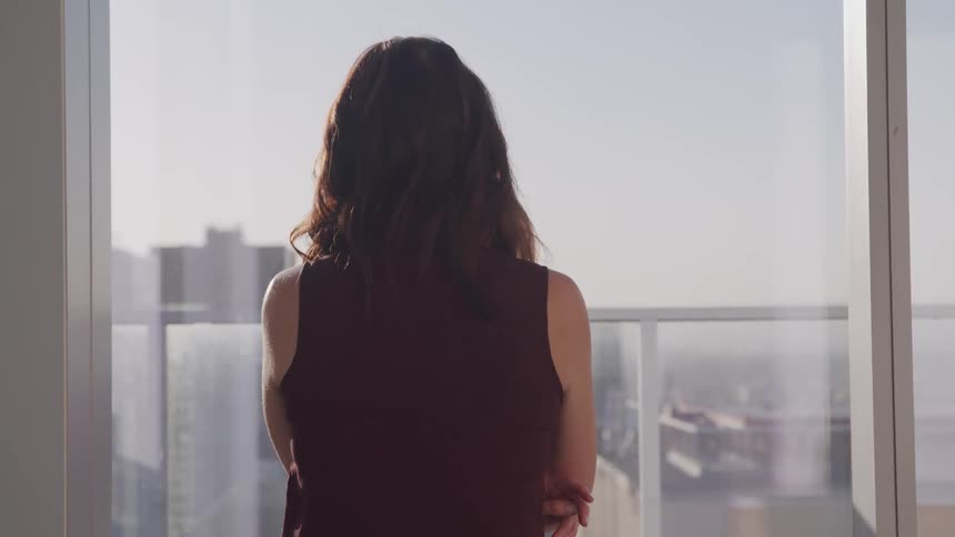 Businesswoman with black wavy hair looks out the office window