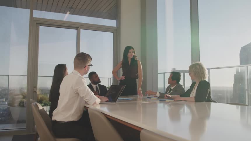 Business people sit at a long table conduct a meeting in conference room