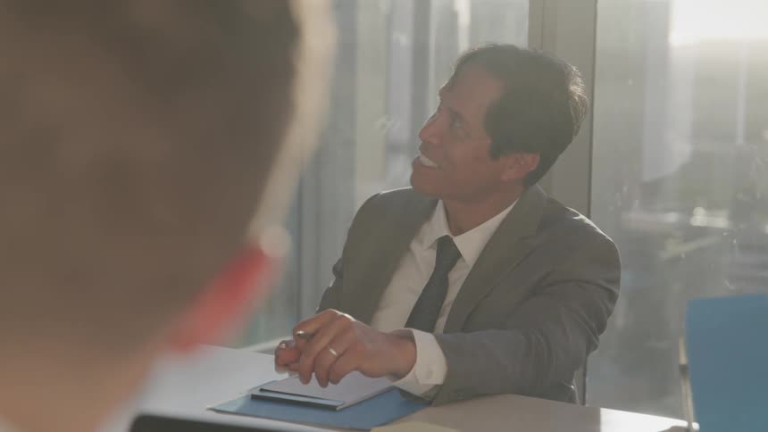 Three people sitting at a table in an office building