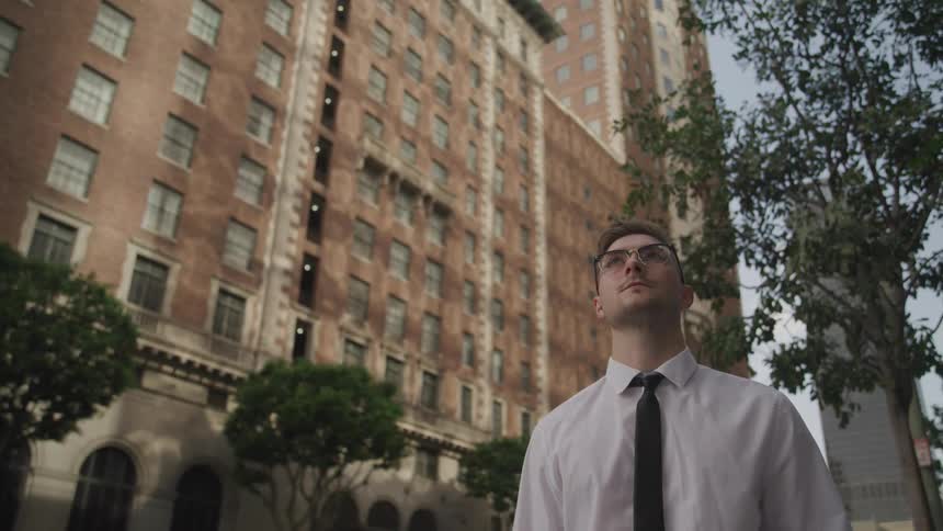A man is standing outdoors in a downtown city