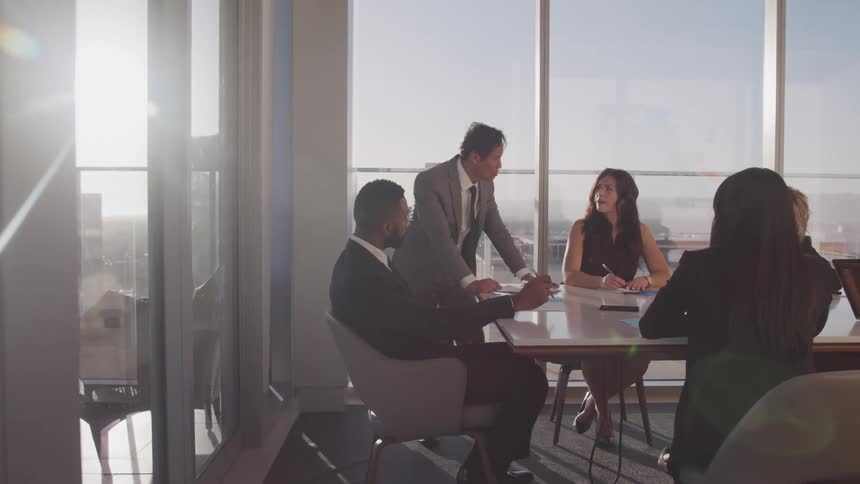 Business people sitting at a long table hold a meeting in the conference room