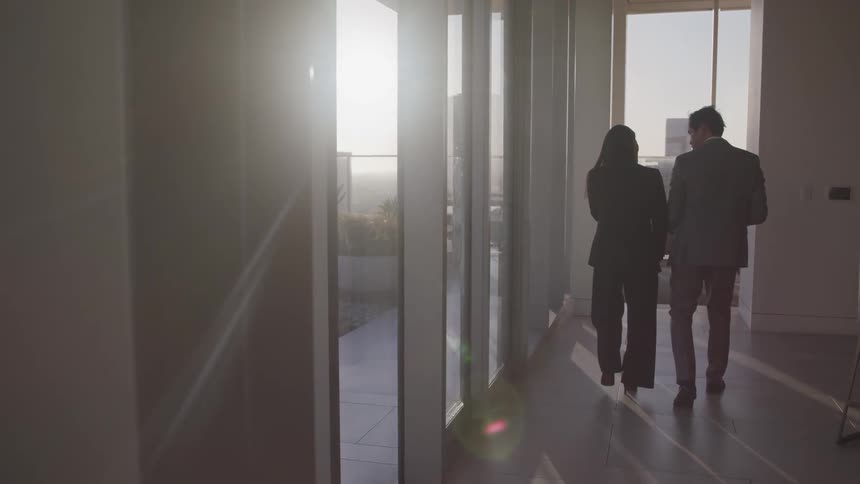 A man and a woman in suits walking towards a conference room