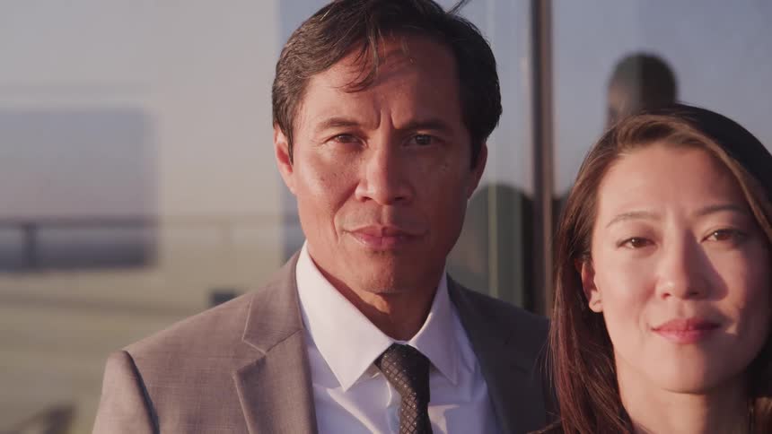 Asian businessman and businesswoman face the camera with eye contact