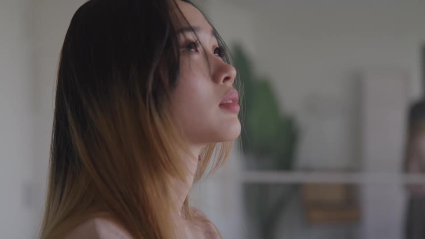 Side view of an asian woman looking up at the ceiling in a room