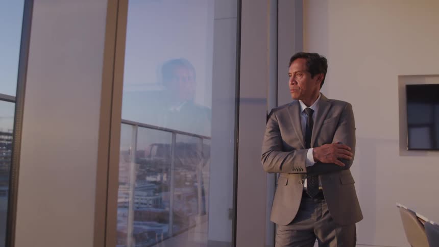 A man staring out a window of an apartment at a city