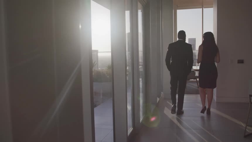 A man with a suit and a woman with a dress walking towards a conference room