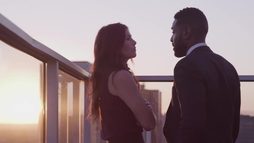 A man and woman standing on a rooftop talking