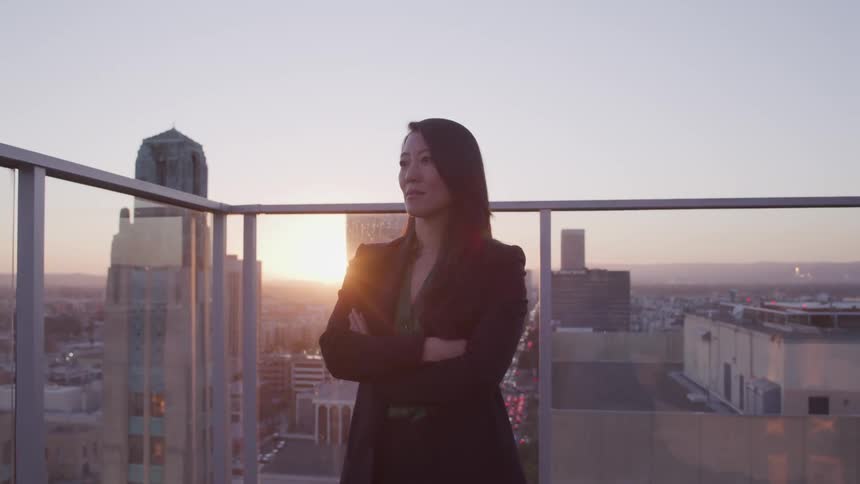 A woman is standing outdoors on a balcony in a large city