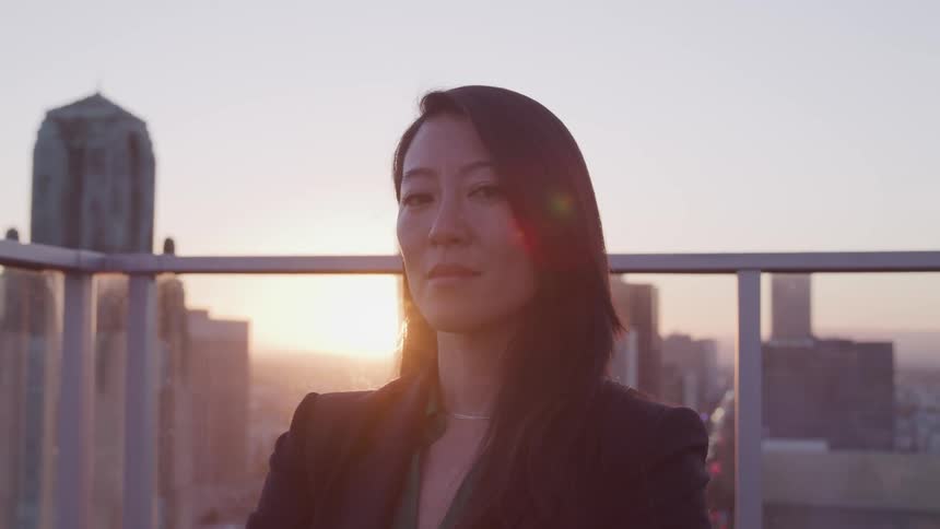 A woman standing on a rooftop with the city skyline behind her