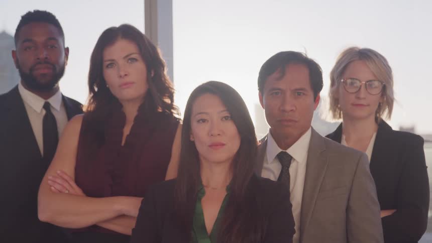 Group of business people looking at the camera in front of city skyline at sunset