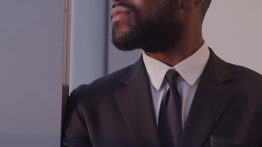 Black businessman with a beard and a suit looks out the window