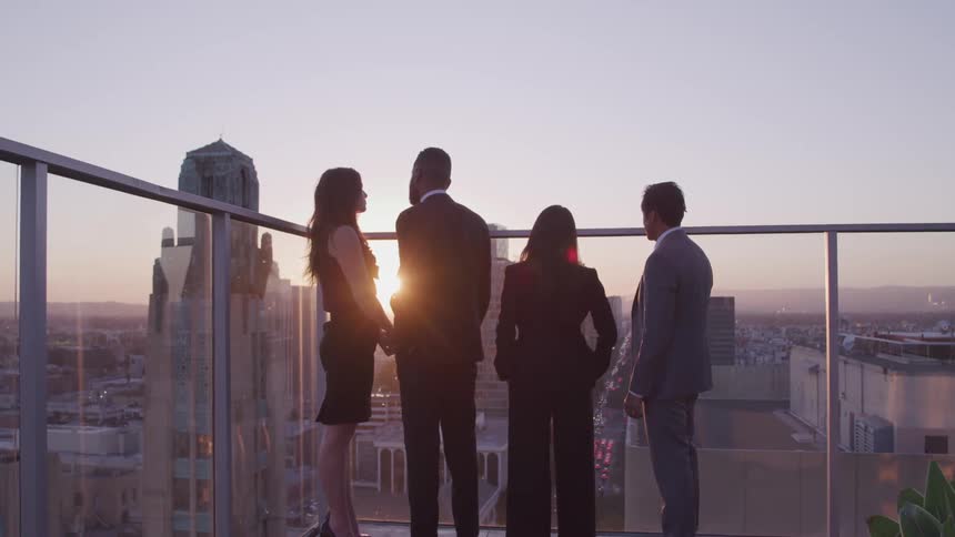 Businessmen and businesswomen stand and talk to each other on the office balcony