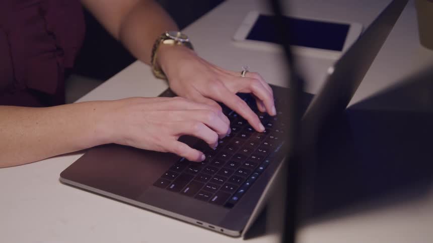 A woman is typing on a laptop indoors