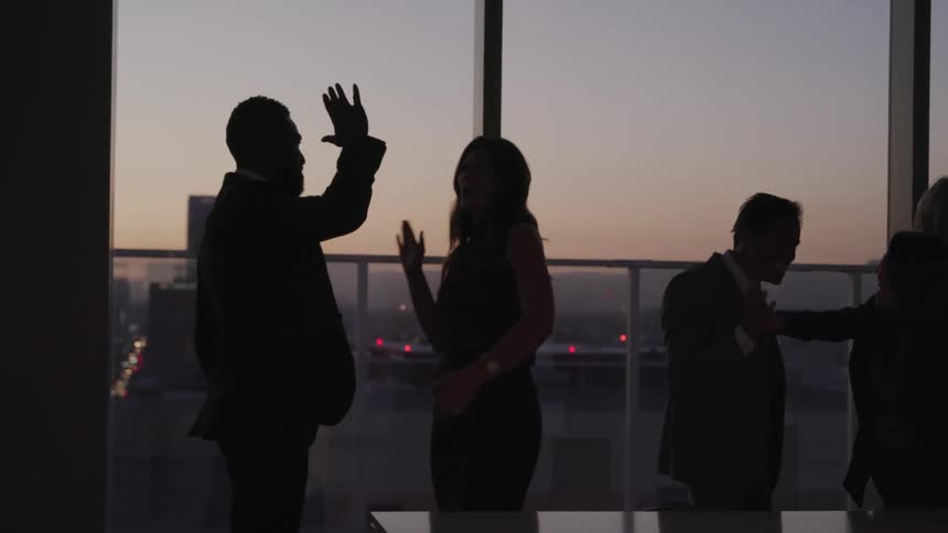 Silhouette of a group of business people celebrating in a meeting room in the office at sunset