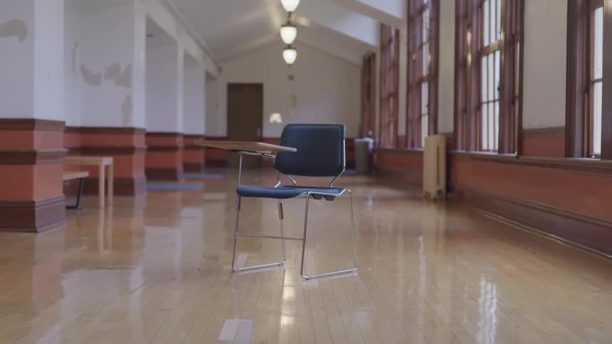 A single desk sitting on a wood floor in a large building