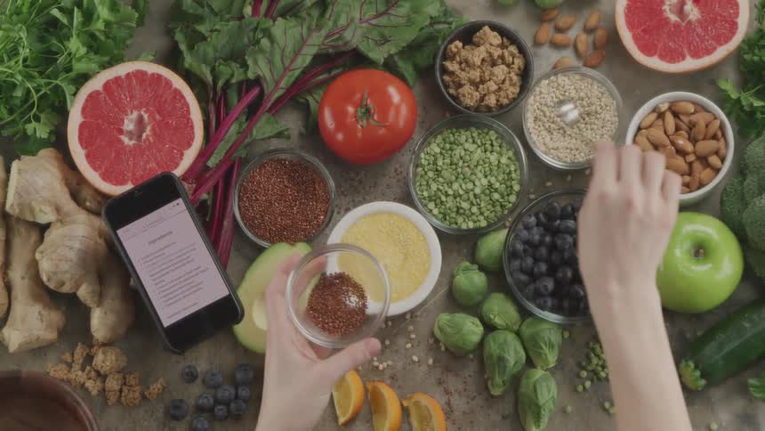 A woman spooning spices in to a bowl as she cooks