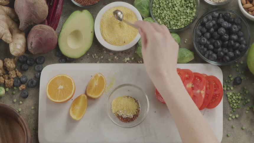 A woman puts spices in a bowl as she cooks