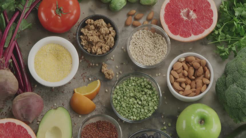 Various types of vegetarian organic food displayed in bowls or sliced over a table