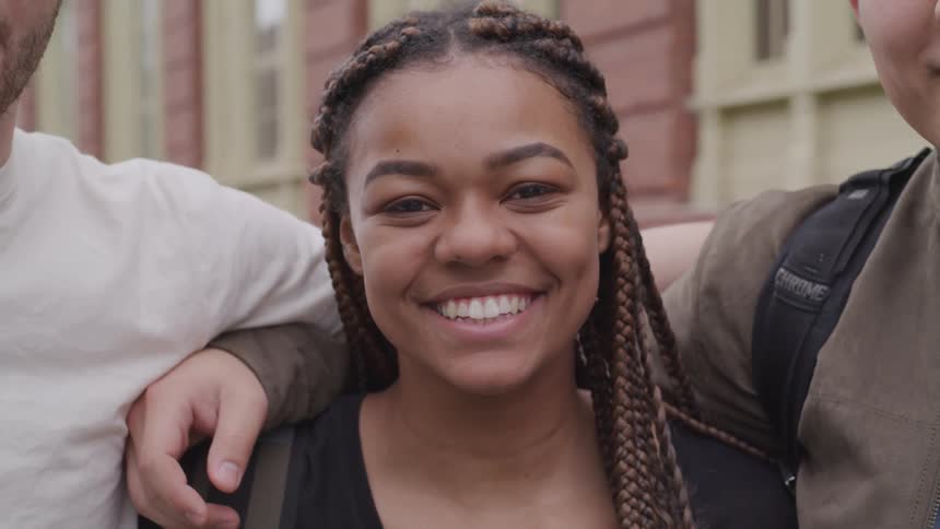 Three people standing close together and the female is smiling